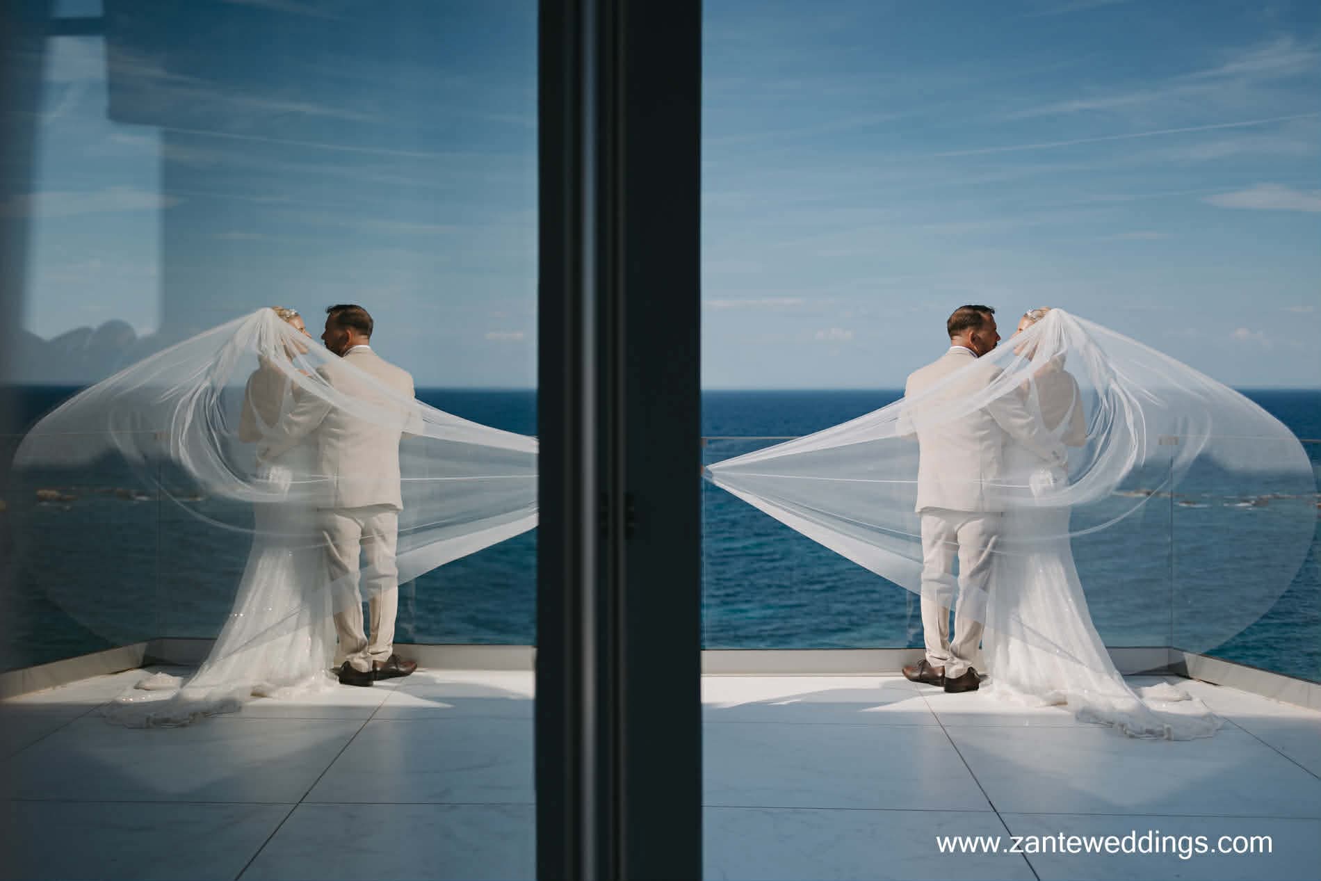 bride and groom looking over the ocean with flying veil